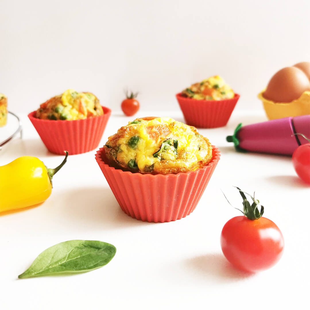 Aubergine muffins next to some cherry tomatoes and a case of eggs