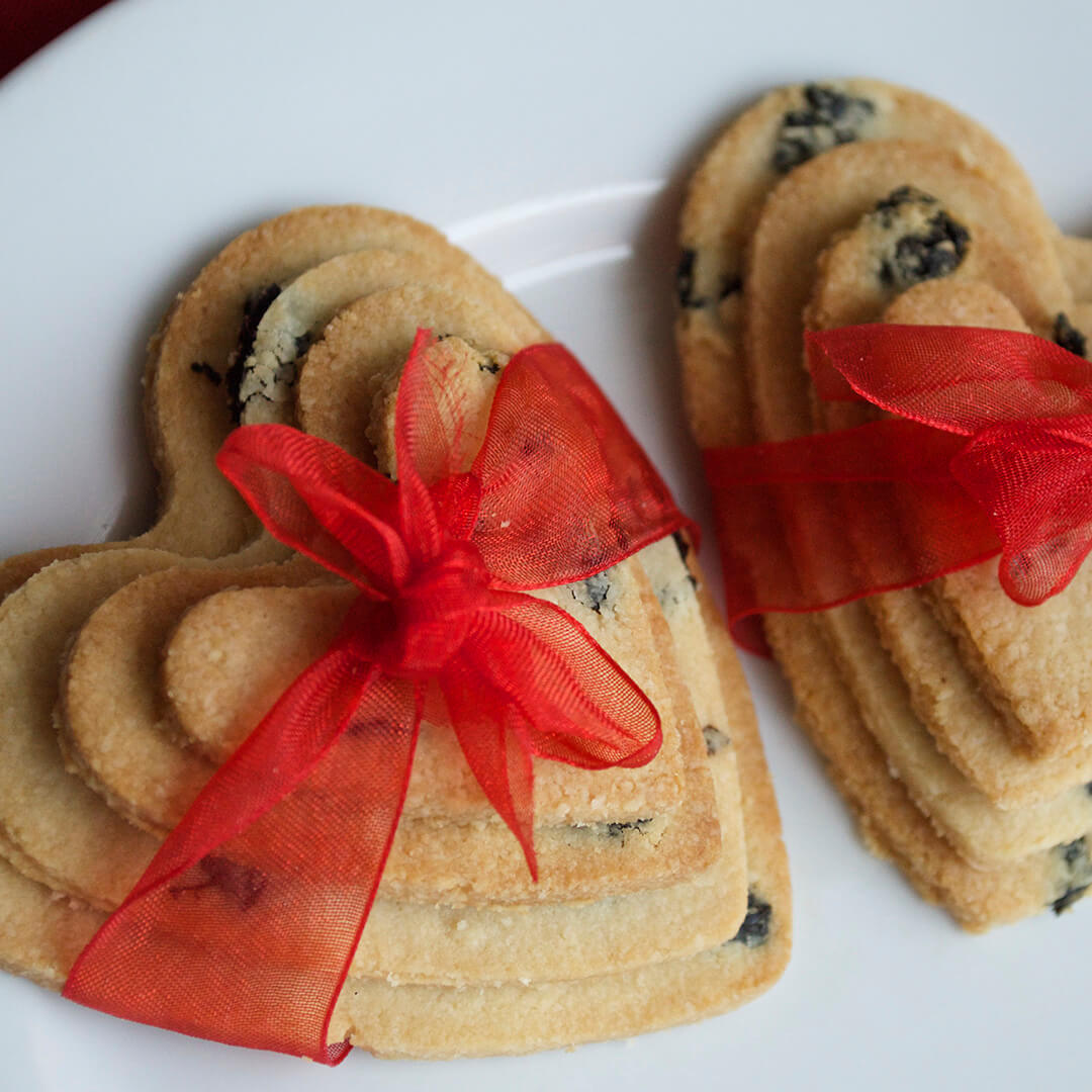 Two stacks of 4 love heart biscuits stacked from biggest to smallest and each tied with a red bow