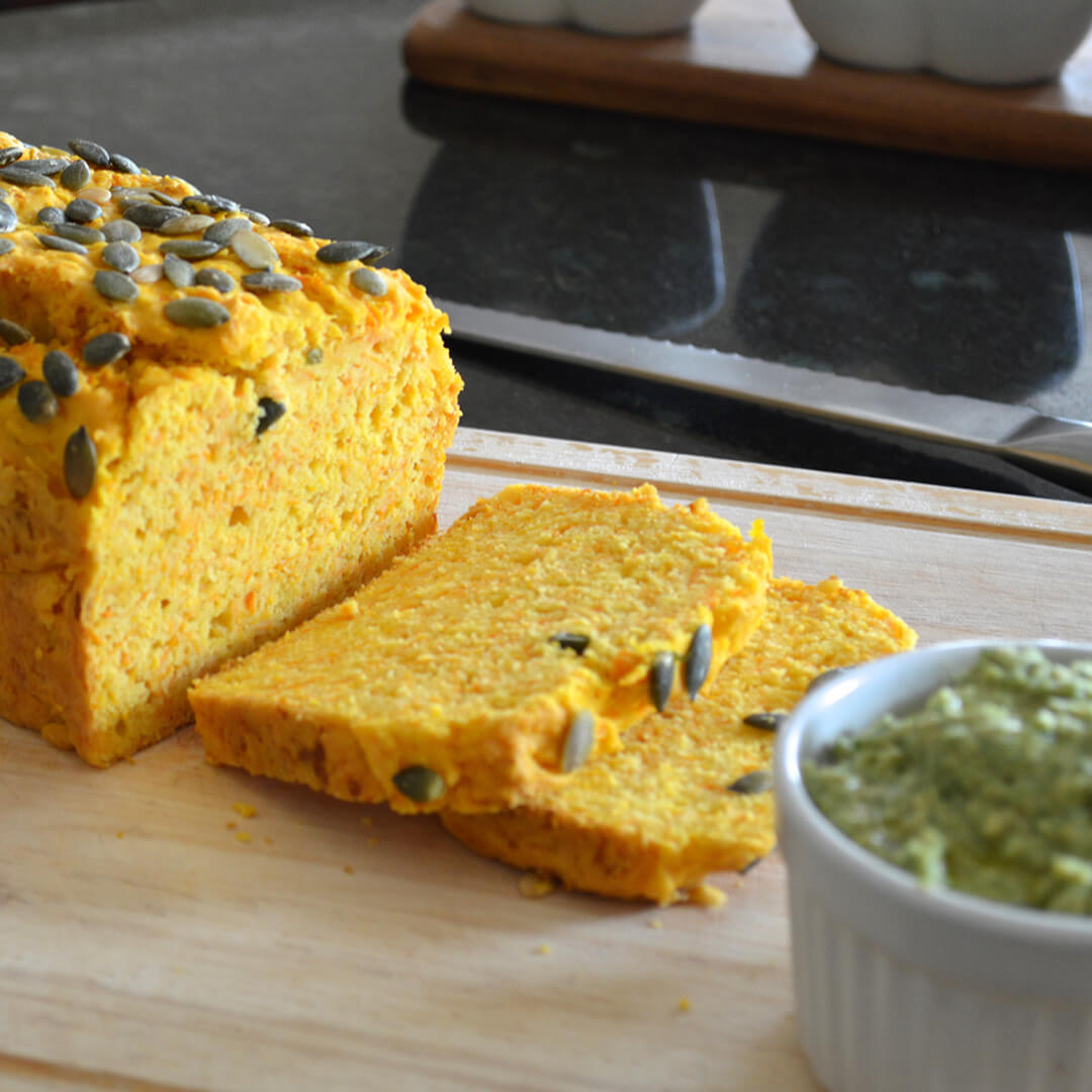 Loaf of Sliced Pumpkin Bread with two sliced cut next to a small jar of dip