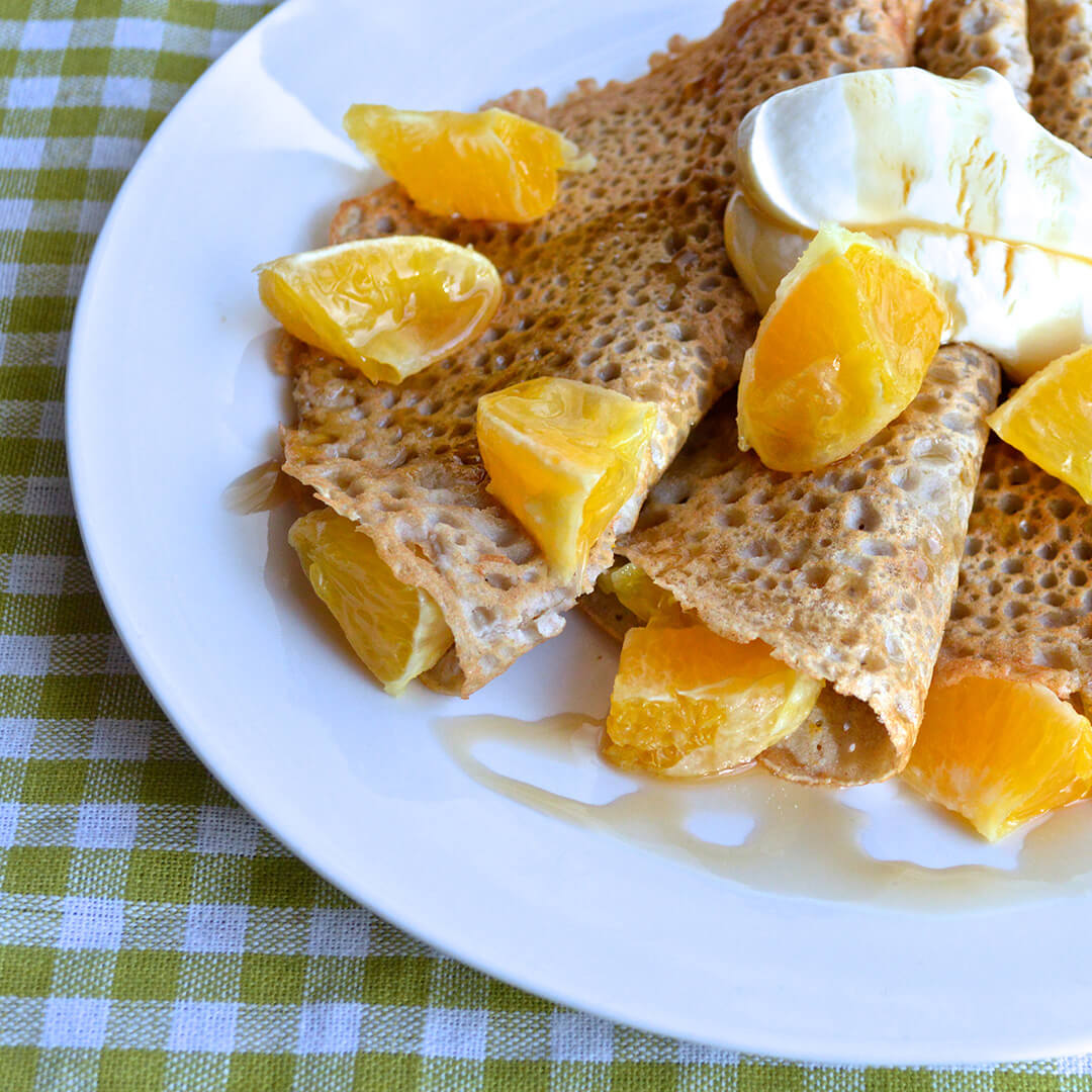 Pancakes with orange segments, Greek yoghurt and drizzled with maple syrup