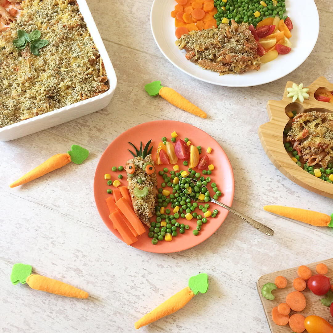 3 servings of vegetable pasta bake served with carrots, peas and sweetcorn next to a casserole dish of vegetable pasta bake