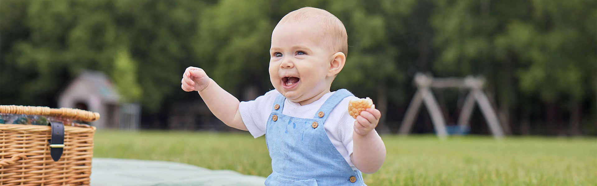 Happy baby eating snack, in the park