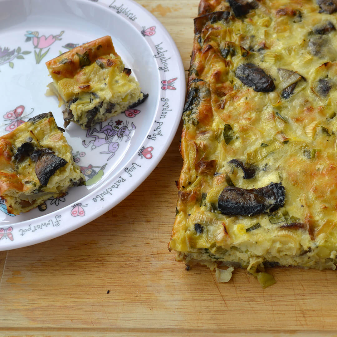 A serving of Artichoke, Mushroom & Leek Frittata next to a frittata