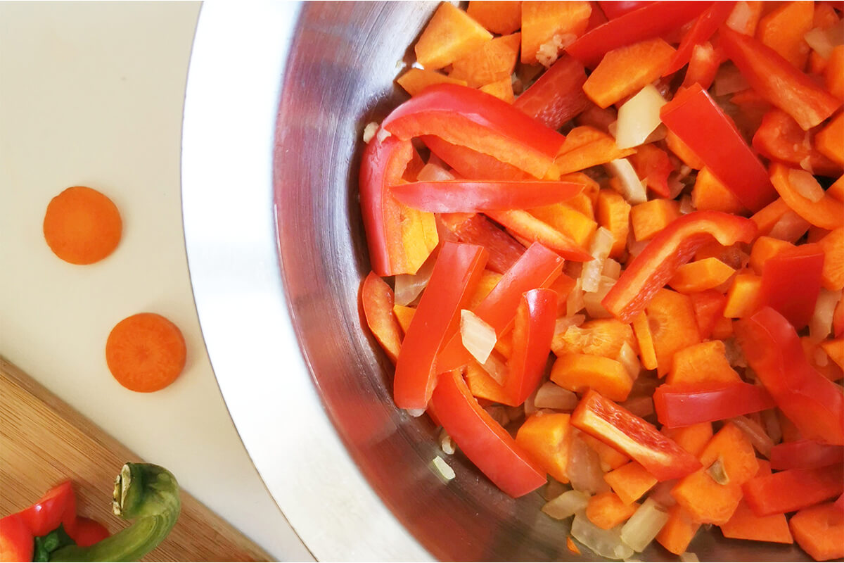 A saucepan of onions, carrots and peppers