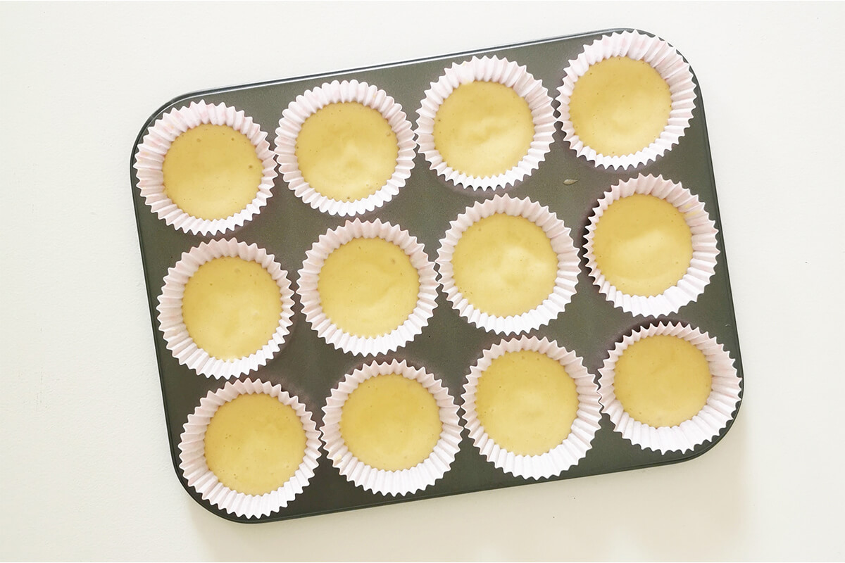 Cupcake batter in paper cake cases in a cupcake tin