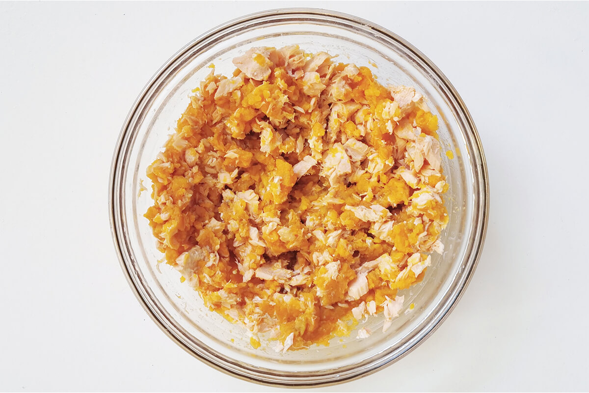 A glass bowl with mashed sweet potato and salmon