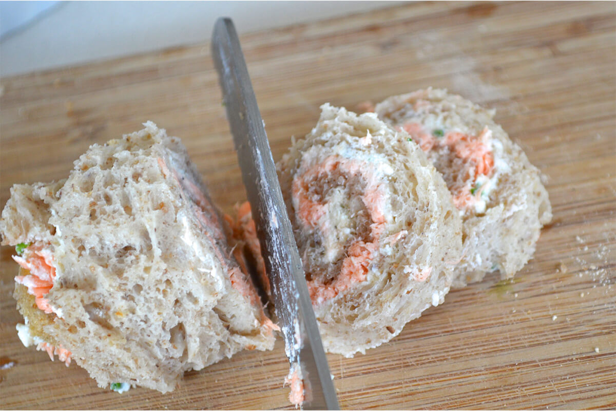 Rolled slices of bread being cut into pinwheels