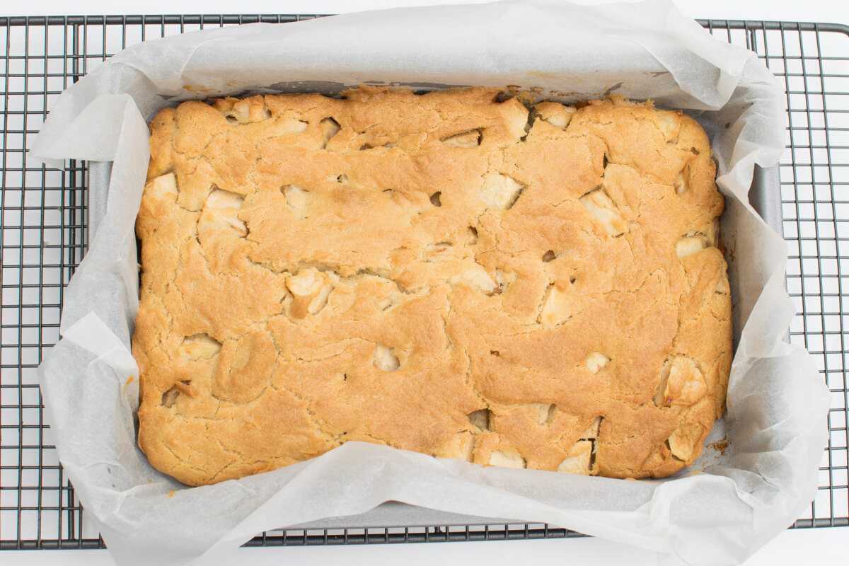 Apple traybake in a baking tin on a cooling rack