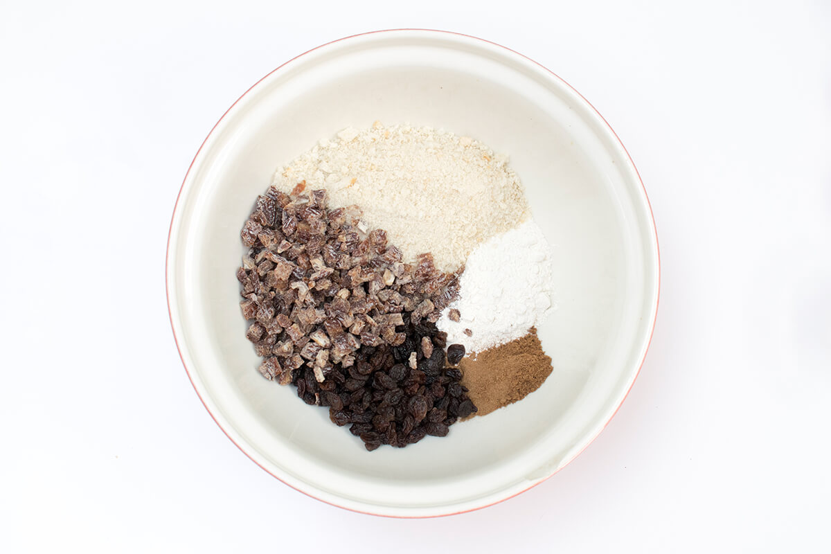 A bowl of flour, breadcrumbs, ground mixed spice, cinnamon, raisins and dates