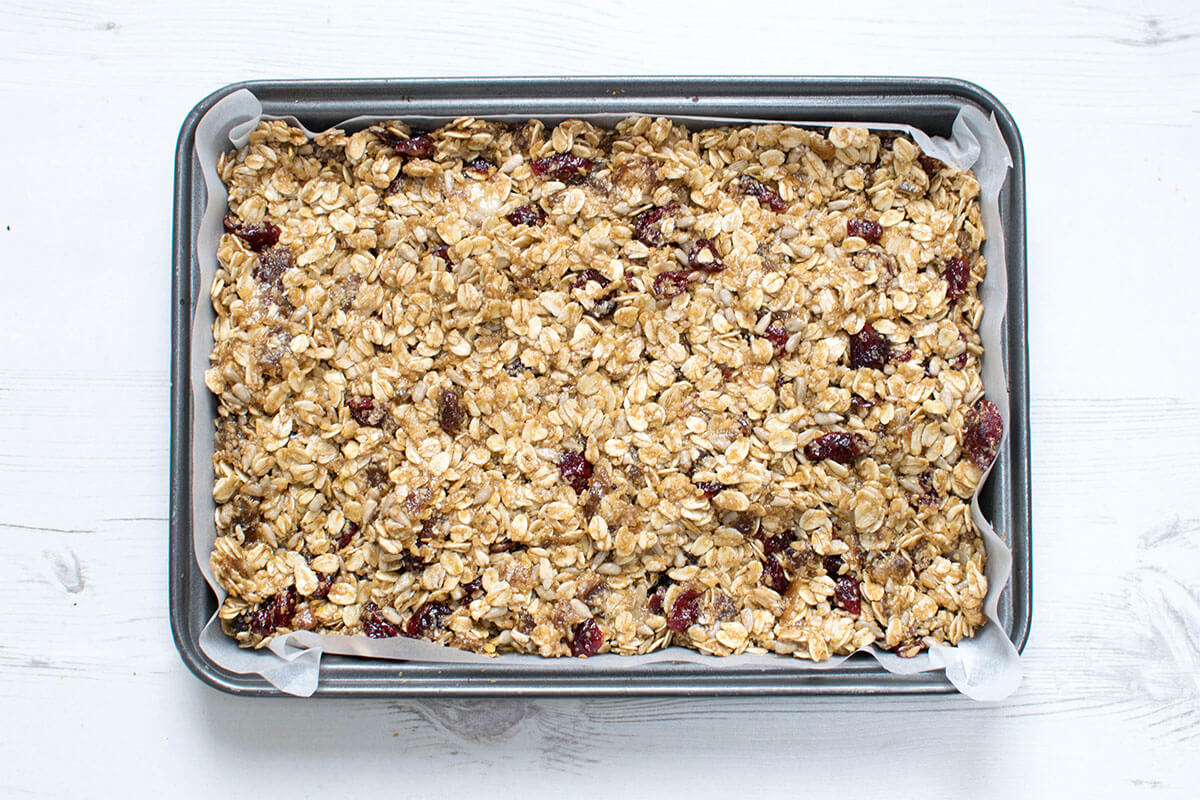 Uncooked date & cranberry seed mix in a lined baking tray