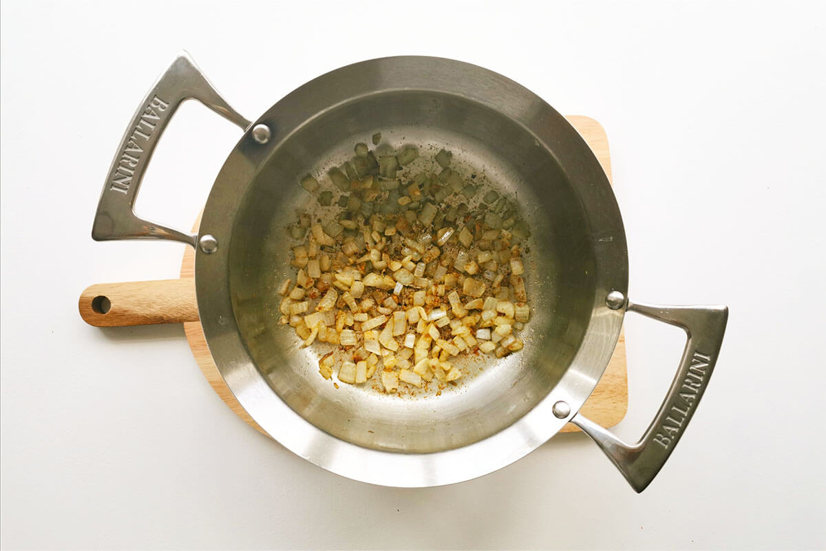 A saucepan with diced onion, garlic and cumin