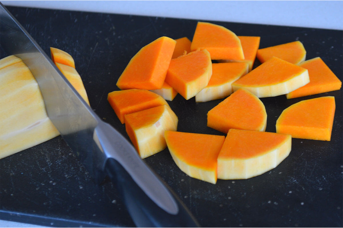 A chopping board with pumpkin being chopped