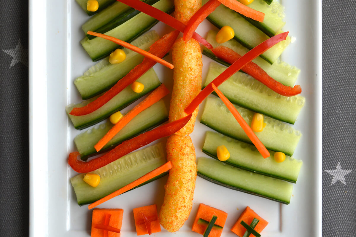 Pepper and carrot placed on top of cucumber tree branches to create tinsel. Sweetcorn placed on top to create baubles