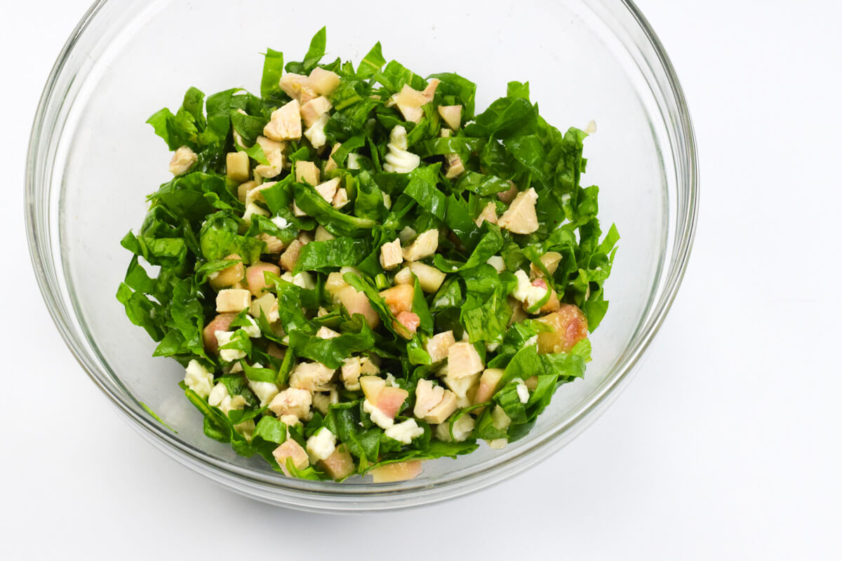 A glass bowl with peach chicken salad