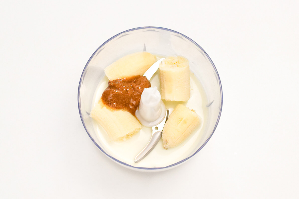 A food processor with banana, milk and peanut butter