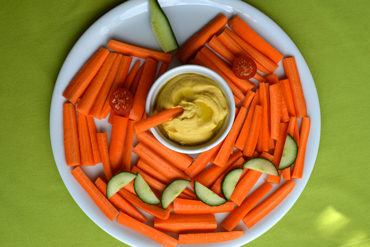 Pumpkin Face Platter made with carrots, cucumber and cherry tomato with a pumpkin hummus dip