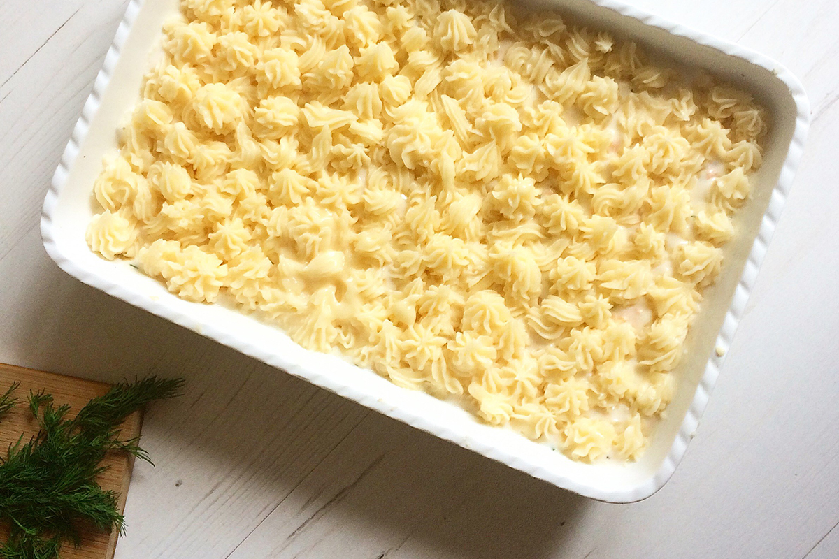 A casserole dish of the leek and salmon mix, topped with mashed potato