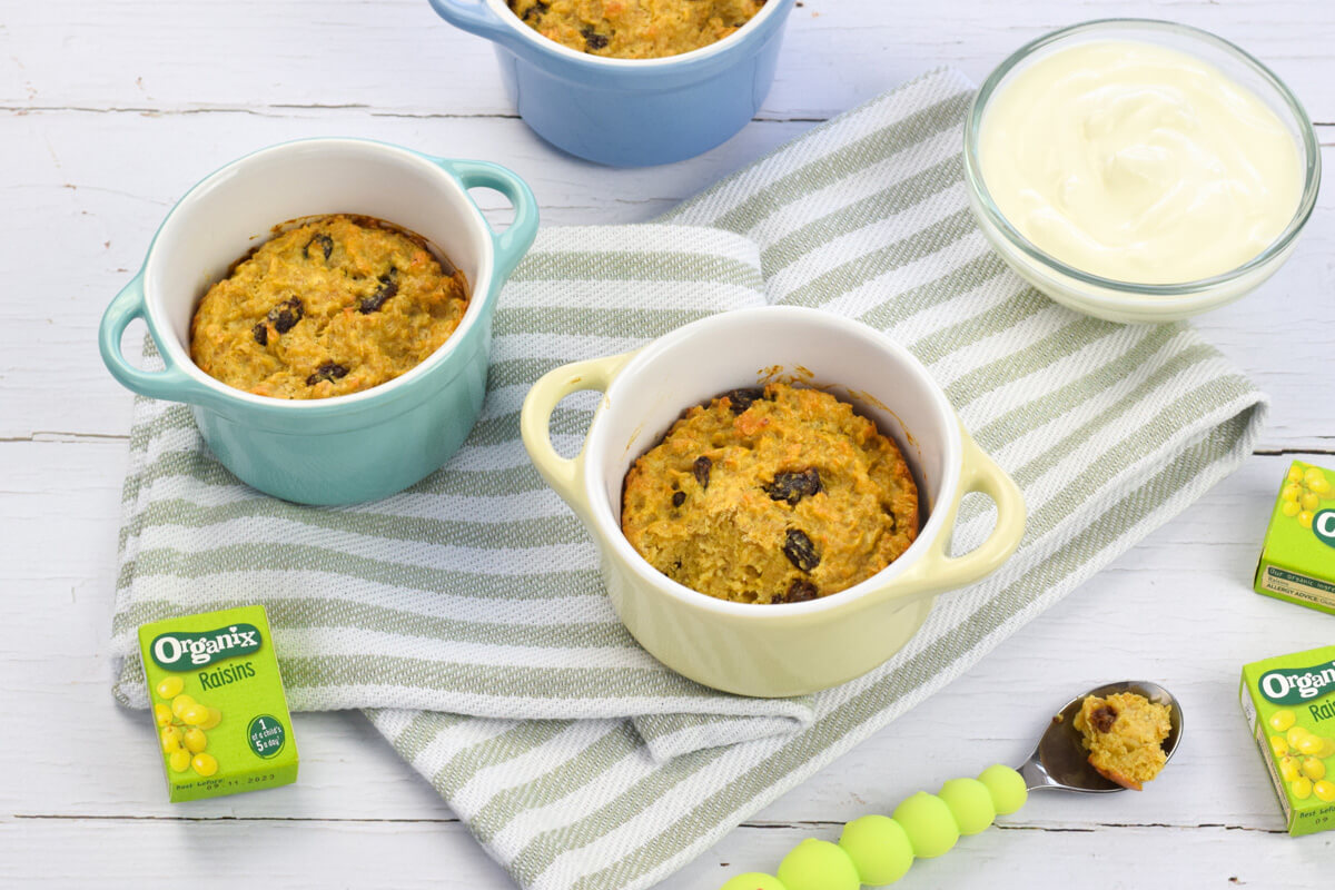 3 small ramekins of vanilla raisin baked oats next to 3 boxes of Organix raisins and a small glass bowl of yoghurt